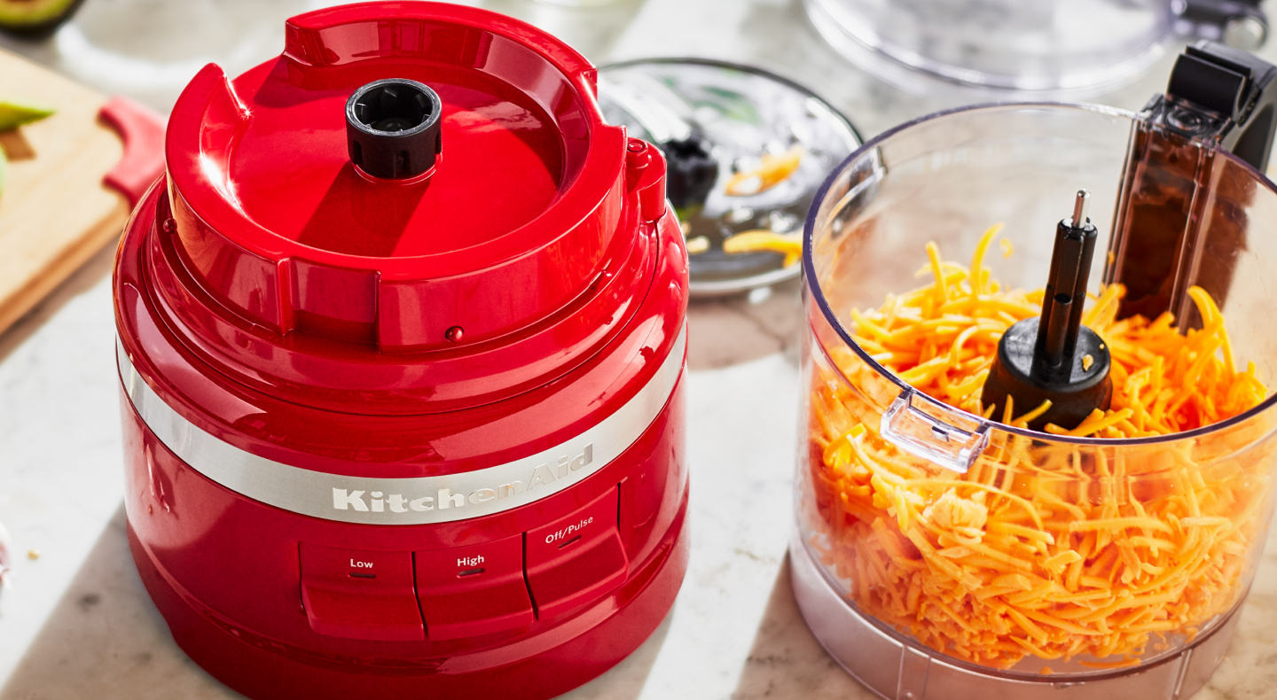 Red KitchenAid® food processor with shredded cheese in it