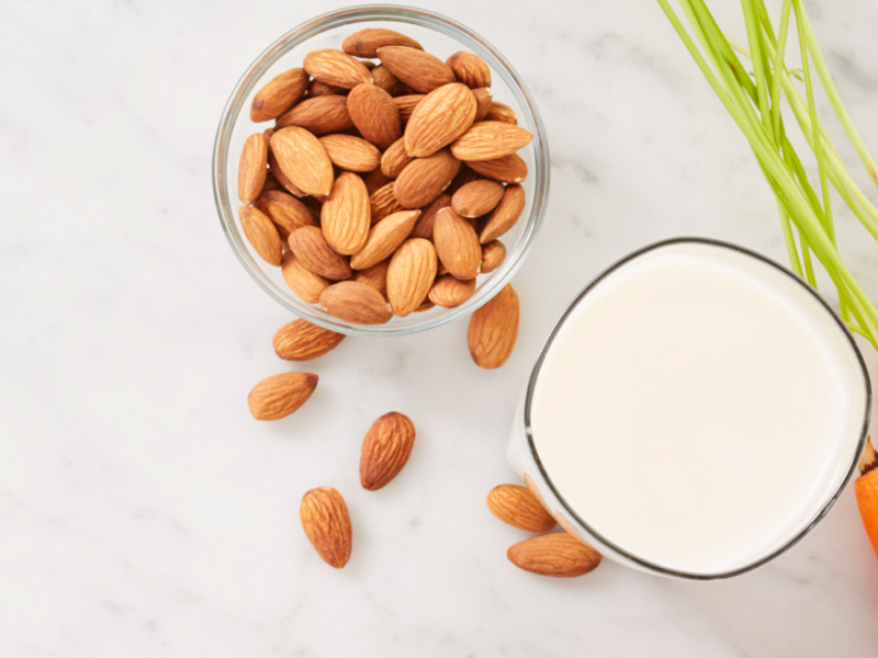 A bowl of almonds and a glass of almond milk