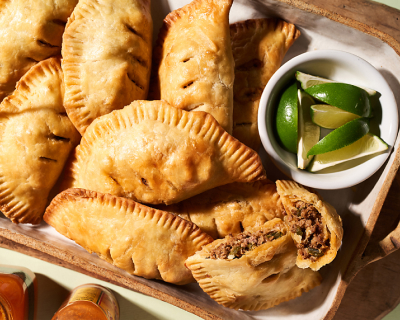 Empanadas on platter next to bowl of lime wedges