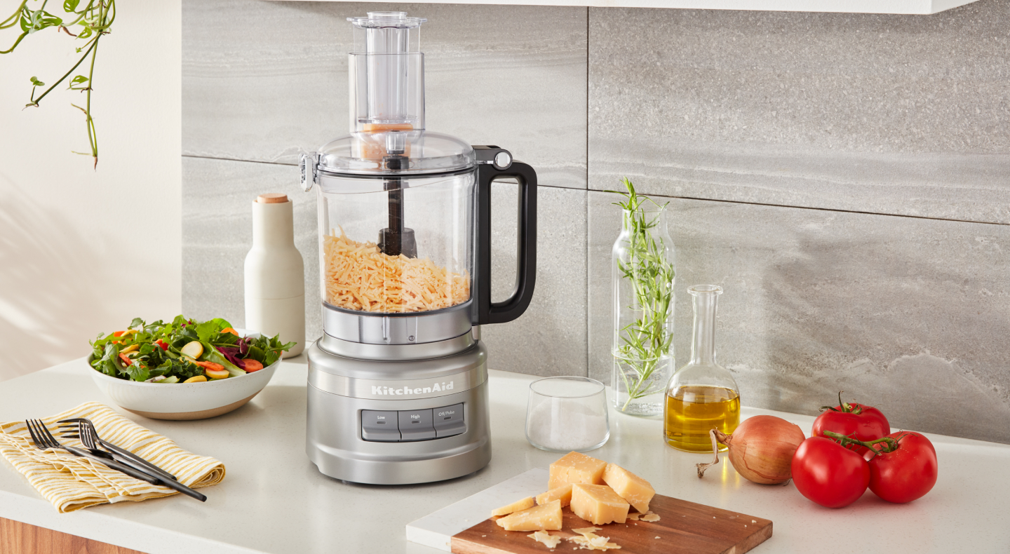 Shredded cheese in a food processor next to a salad