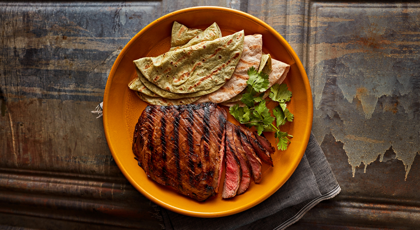Sliced steak and fresh tortillas garnished with herbs