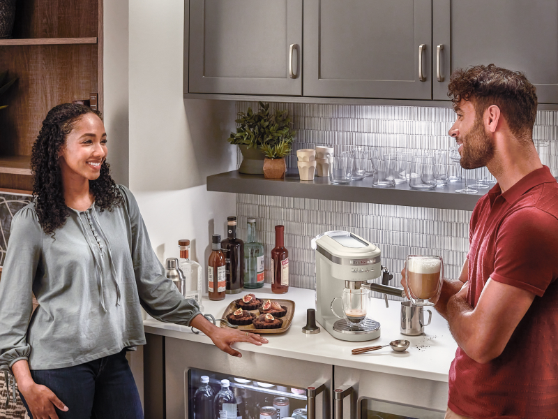 Couple standing at a kitchen coffee bar drinking lattes