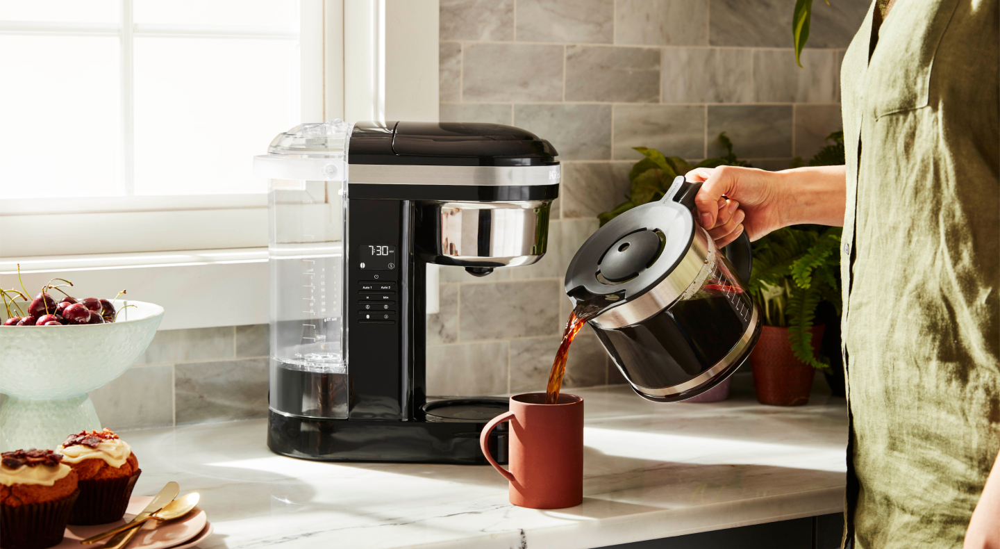 Person pouring a pitcher of coffee into a mug