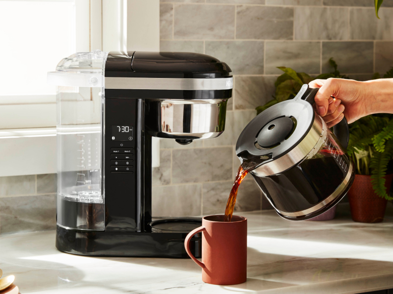 Person pouring a pitcher of coffee into a mug