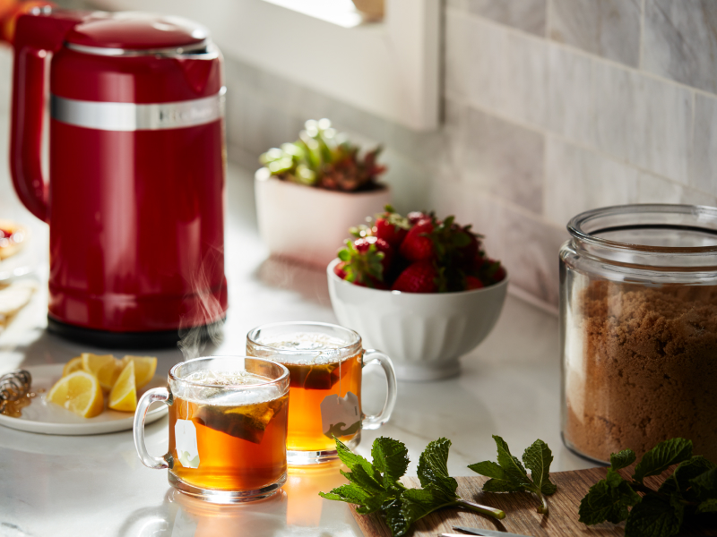 Red KitchenAid® kettle and cups of tea on a countertop
