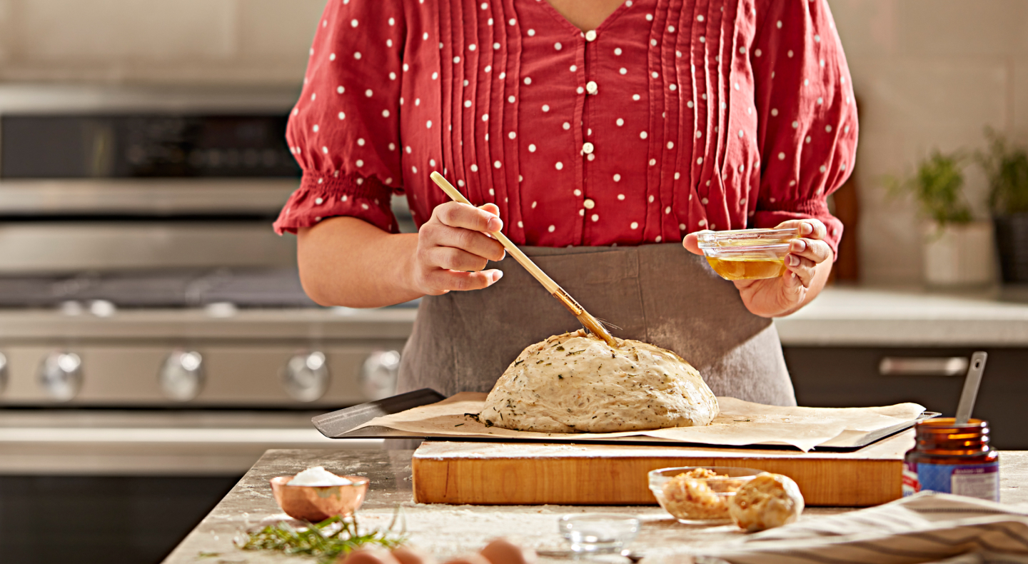 Person brushing egg on bread dough