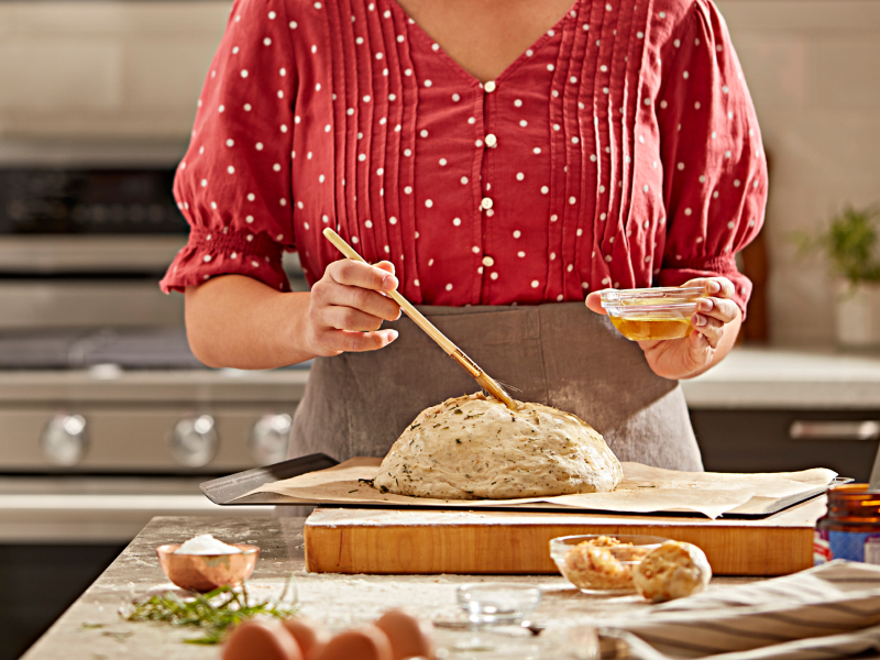Person brushing egg on bread dough
