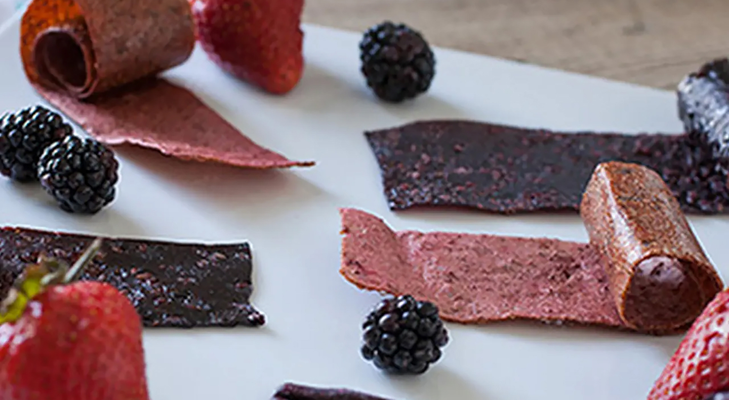Sheets of homemade fruit leather and black berries.