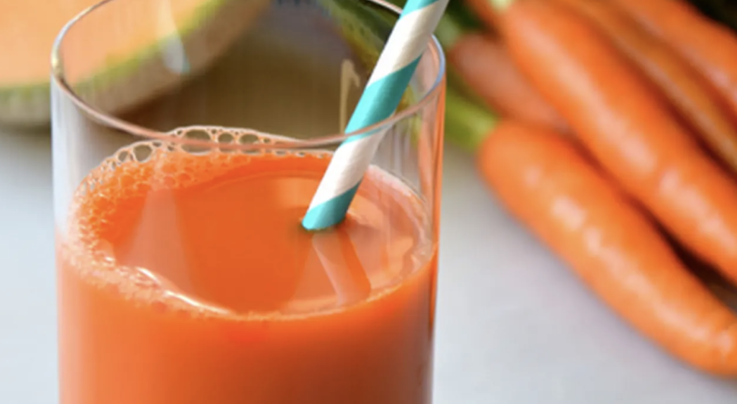 Straw in glass of carrot juice