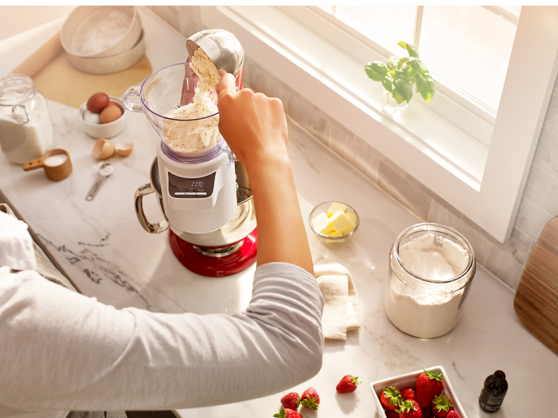Person measuring flour in KitchenAid® Sifter + Scale Attachment
