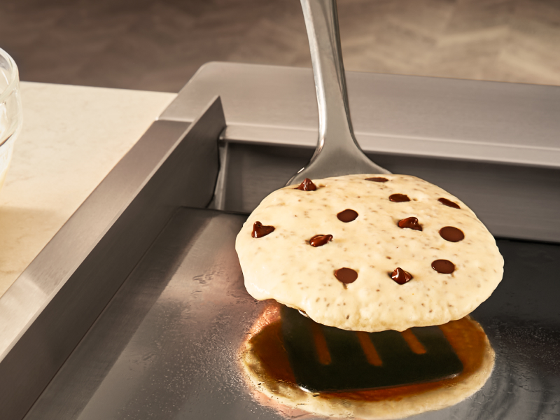 Person flipping chocolate chip pancake with spatula