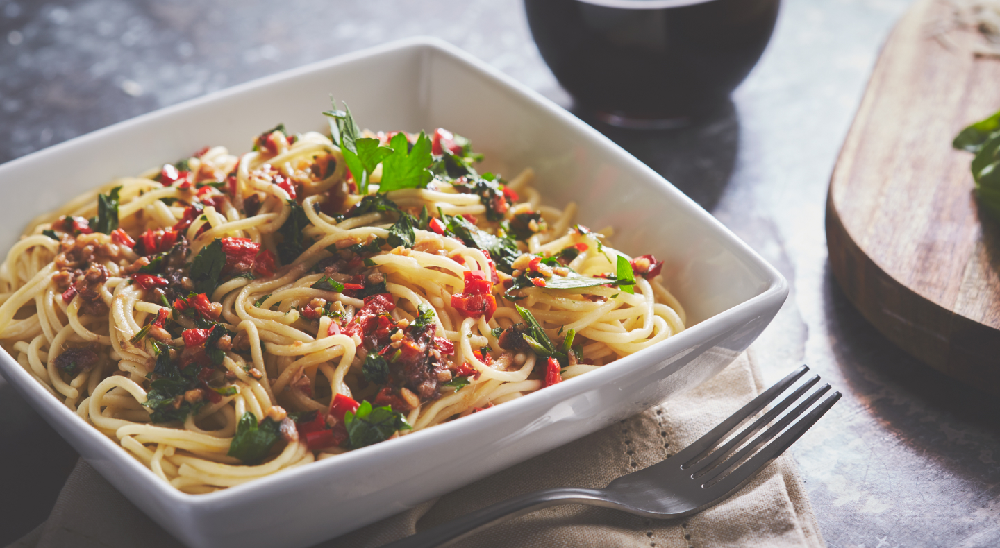 Homemade pasta in square white bowl topped with colorful sauce