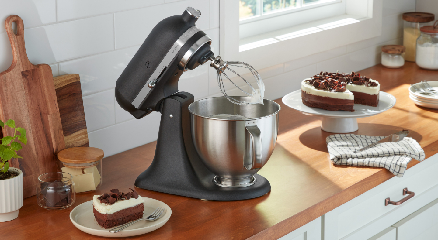 KitchenAid® stand mixer with wire whip next to cake