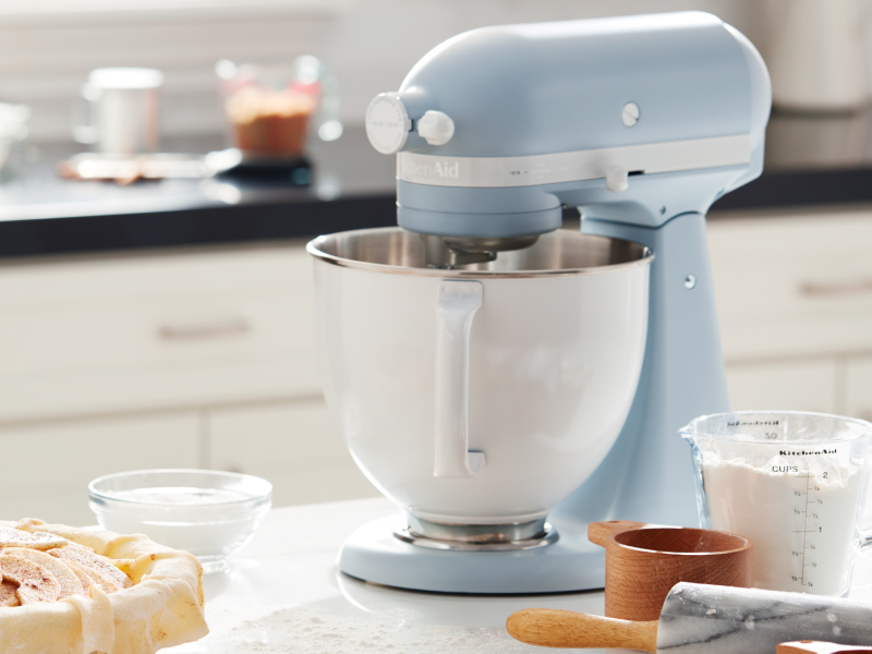 Blue KitchenAid® stand mixer on countertop with baking ingredients and plate of cookies