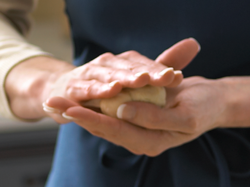 Maker using hands to press down mochi dough