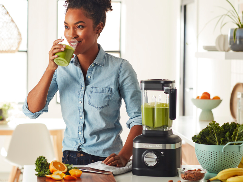 Person drinking a protein shake next to black KitchenAid® blender