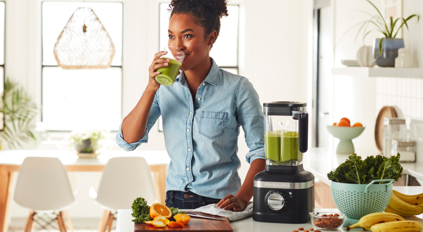 Person drinking a protein shake next to black KitchenAid® blender