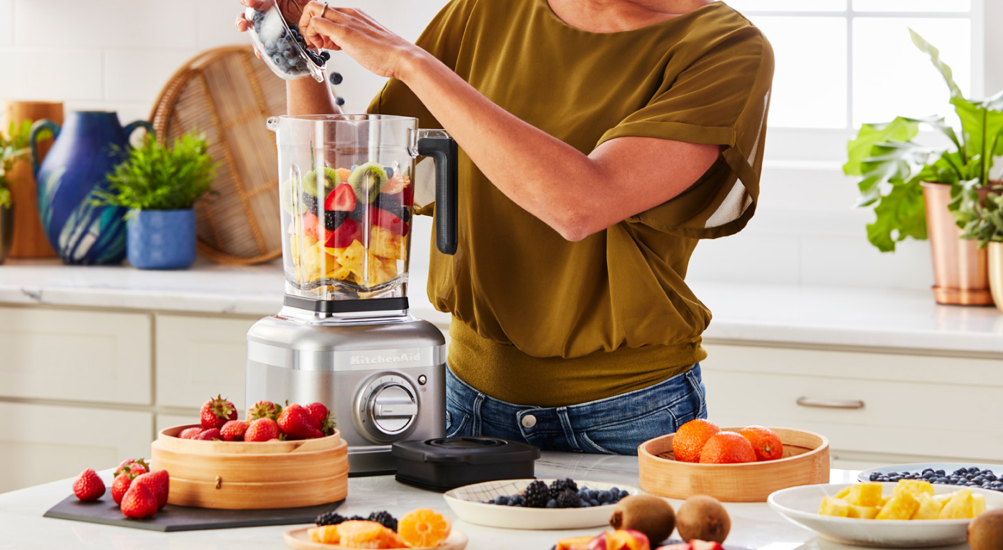 Person adding fruit to a KitchenAid® blender