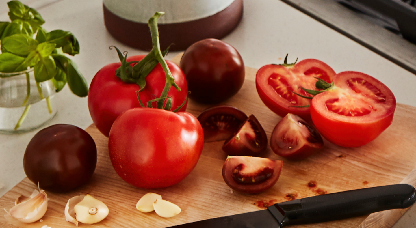 A cutting board piled with tomatoes