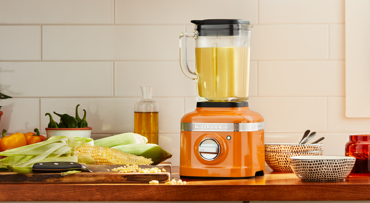 Orange KitchenAid® blender next to corn on the cob