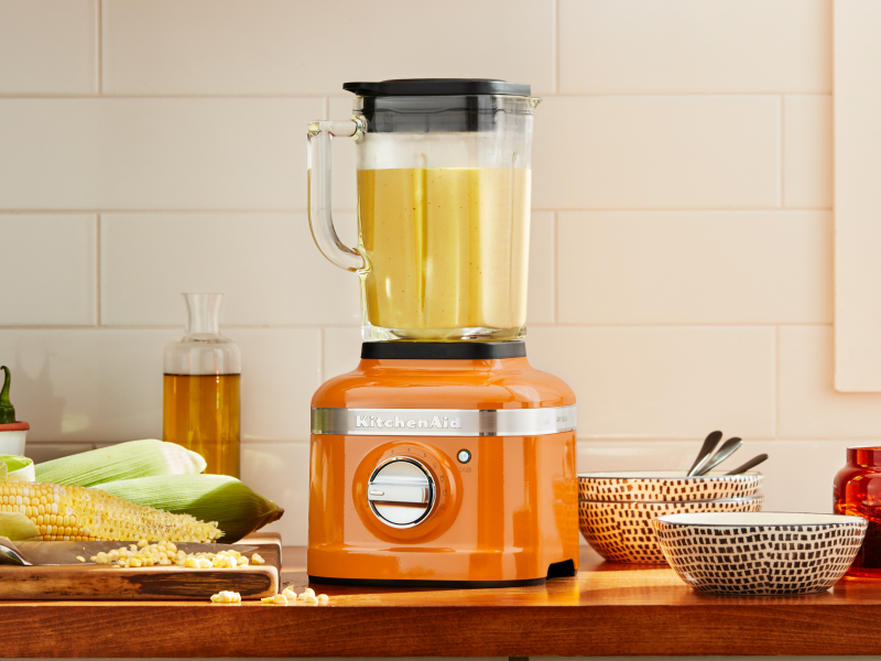 Orange KitchenAid® blender next to corn on the cob