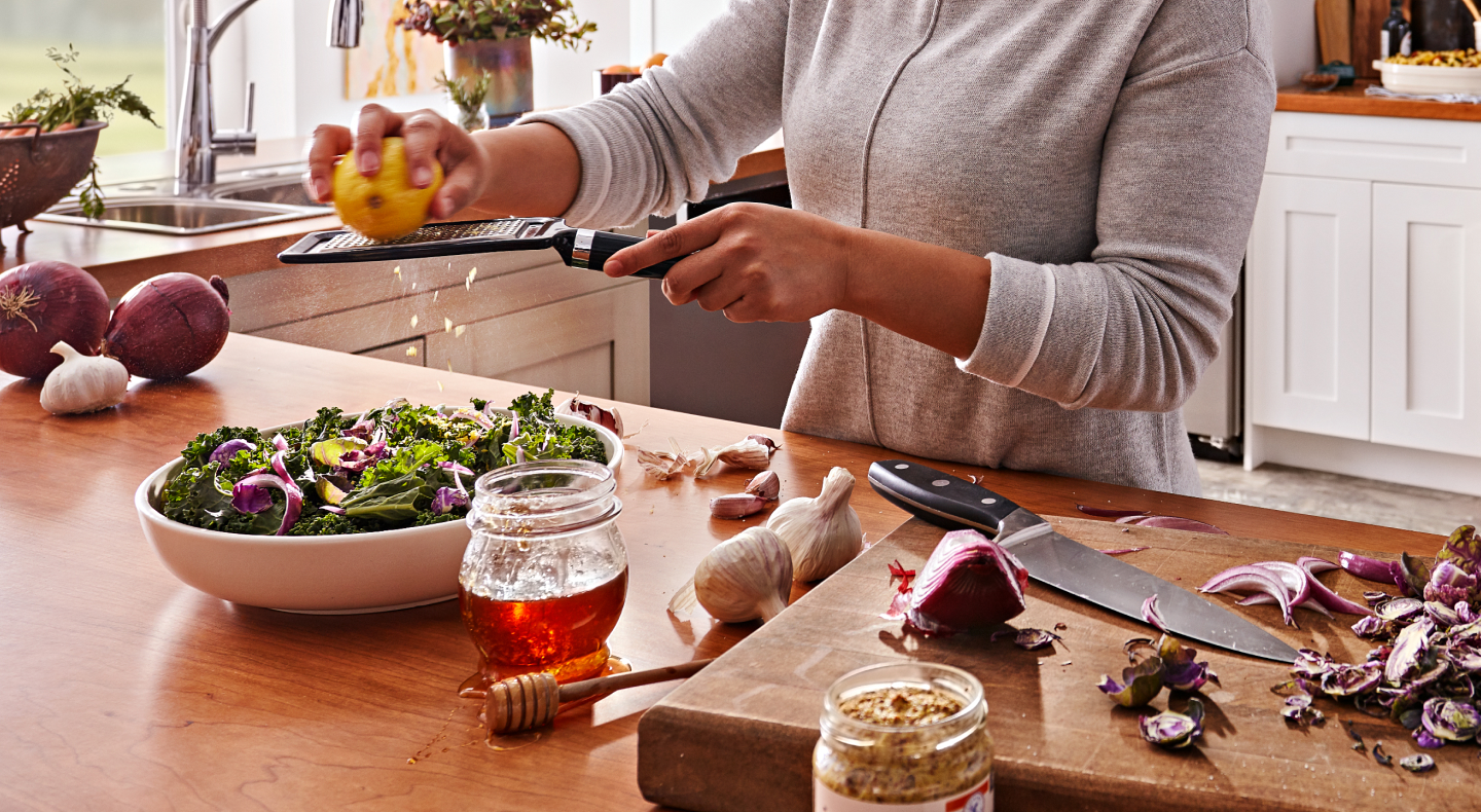 Woman grating citrus over salad