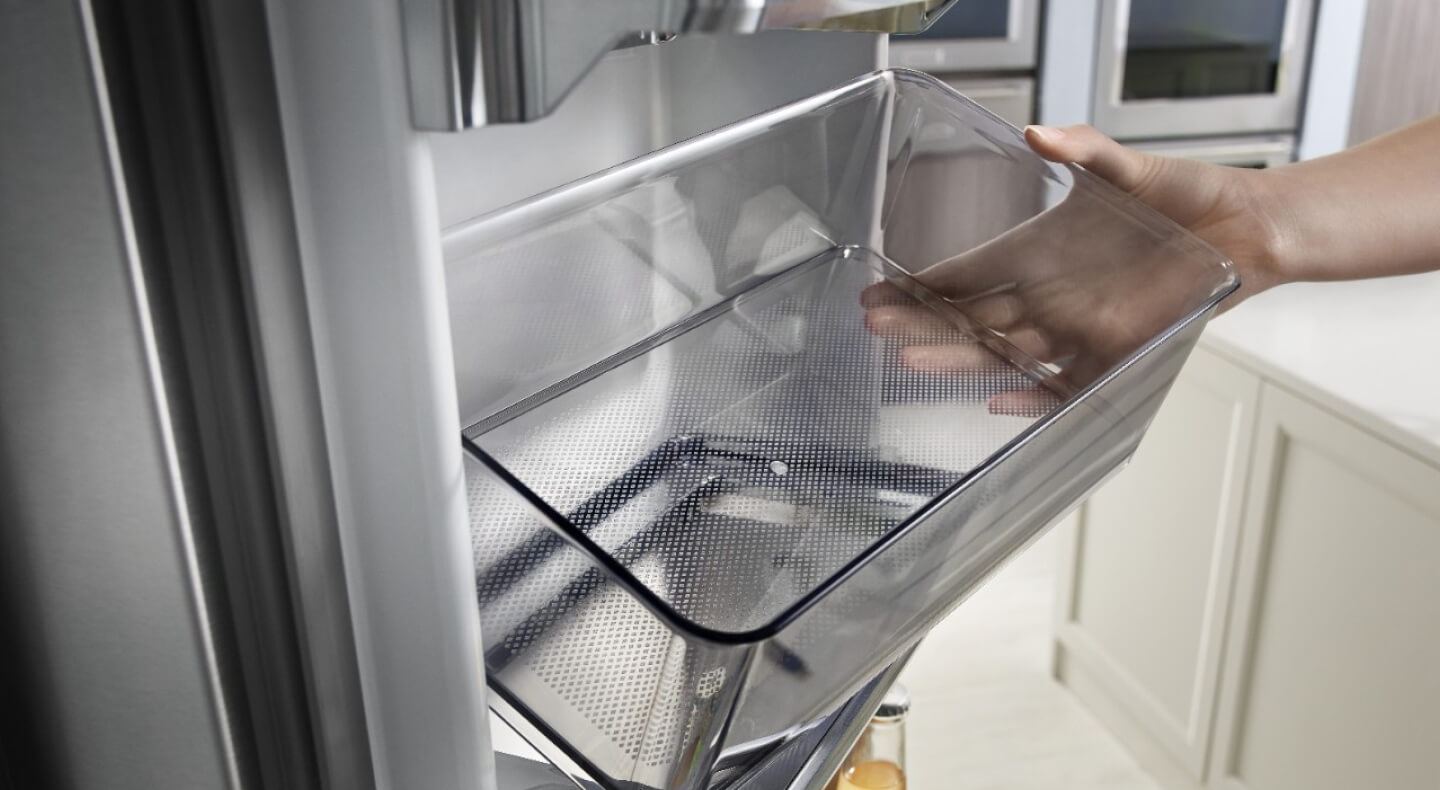Person removing a storage bin from a refrigerator