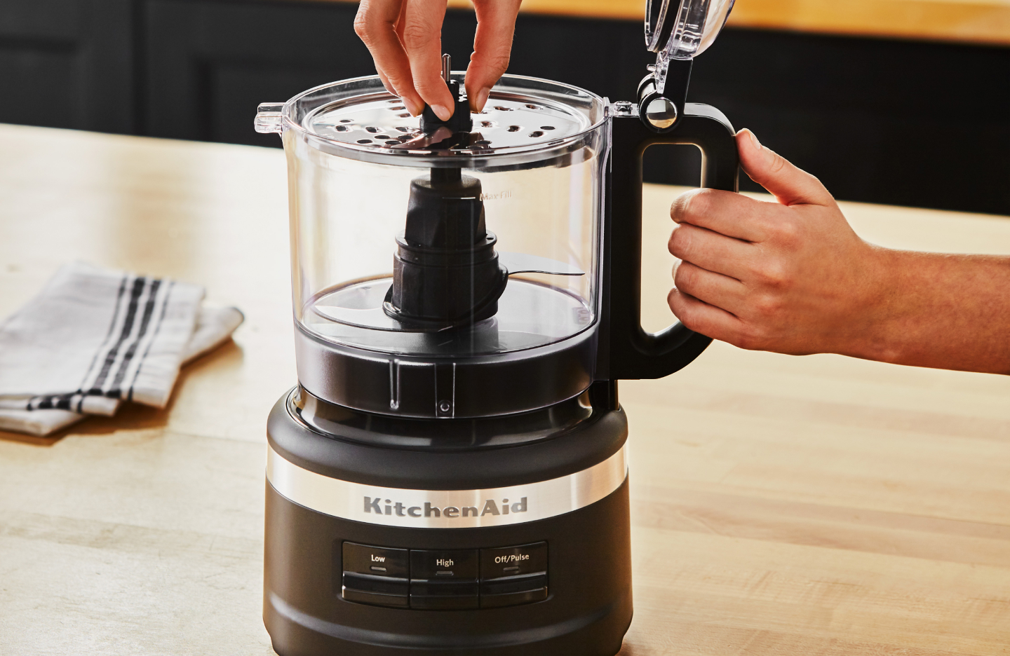 A woman putting a blade into a KitchenAid® food processor