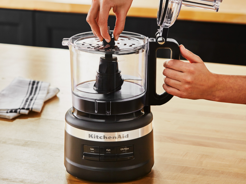 A woman putting a blade into a KitchenAid® food processor