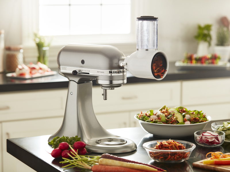 KitchenAid® stand mixer with a fresh prep slicer/shredder attachment in a modern kitchen next to freshly sliced vegetables