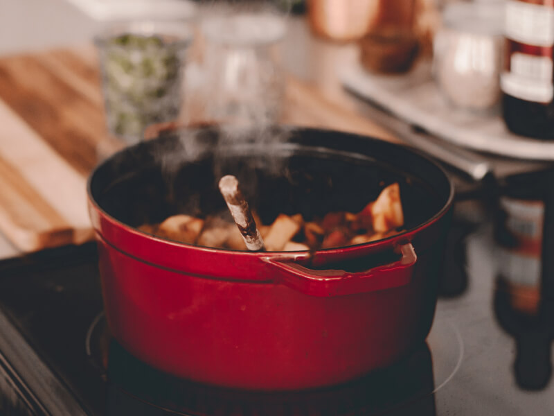 Food cooking in a red Dutch oven