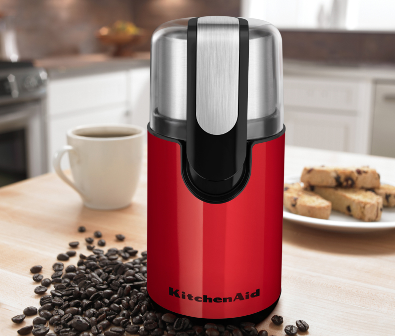 Red coffee grinder on a countertop with beans