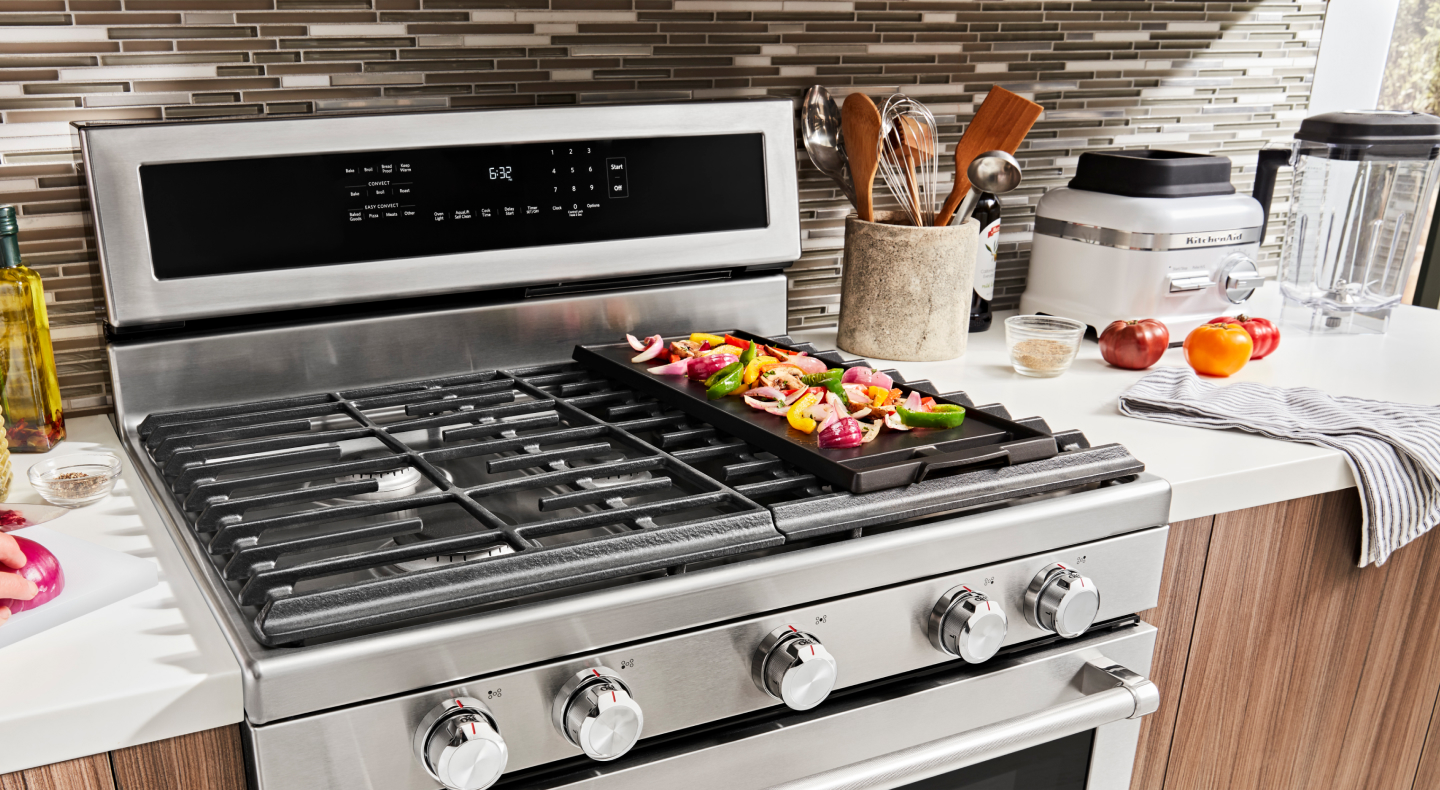 Various ingredients cooking on a gas stove griddle
