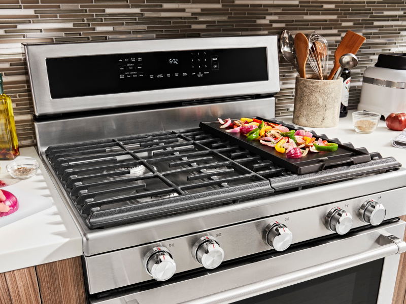 Various ingredients cooking on a gas stove griddle