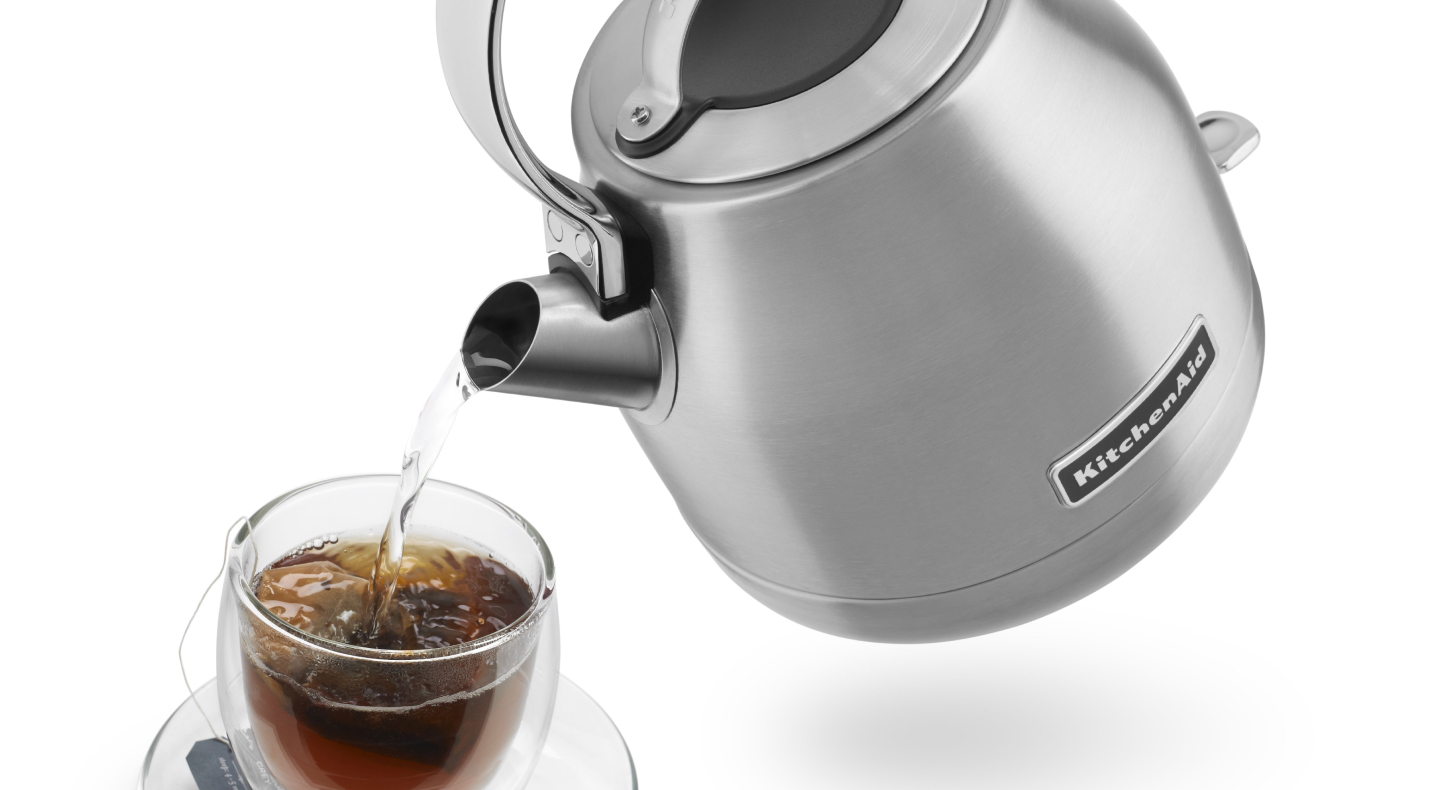 Hot water being poured from KitchenAid® kettle into glass of tea