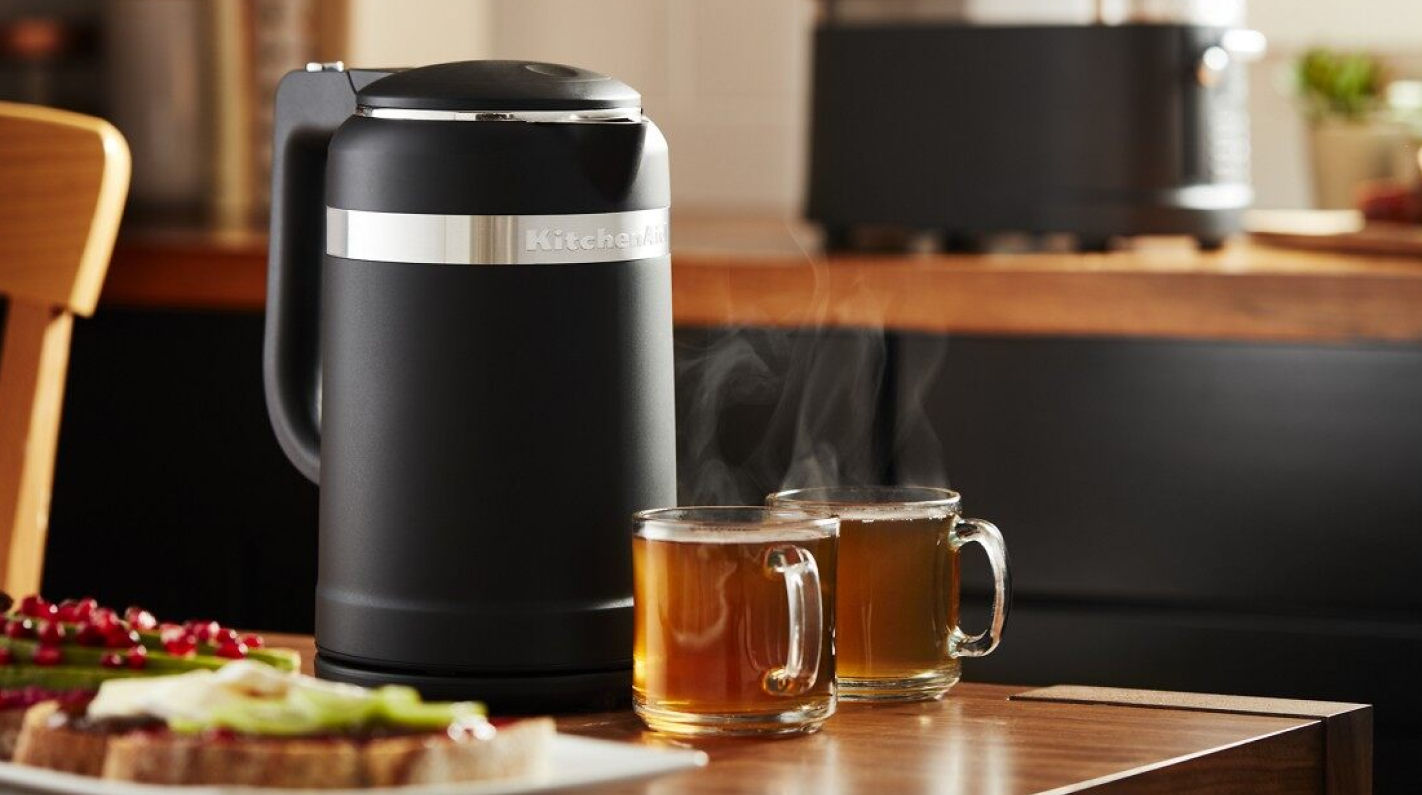 Black KitchenAid® electric tea kettle on table with glasses of tea. 