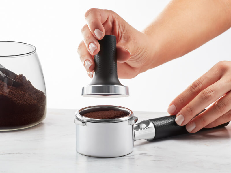 Hand tamping espresso grounds in a portafilter