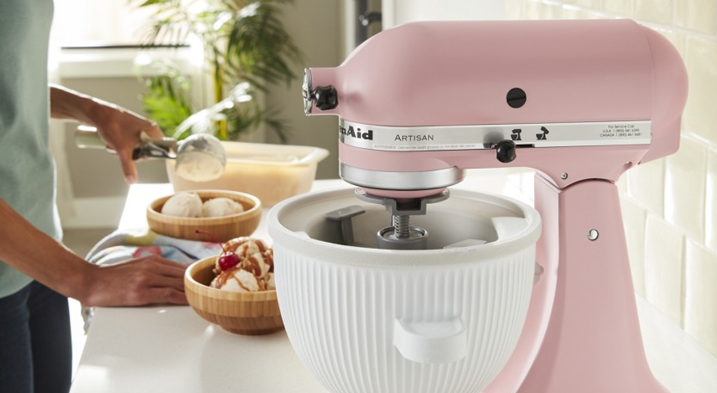 Person making an ice cream sundae next to a pink KitchenAid® stand mixer