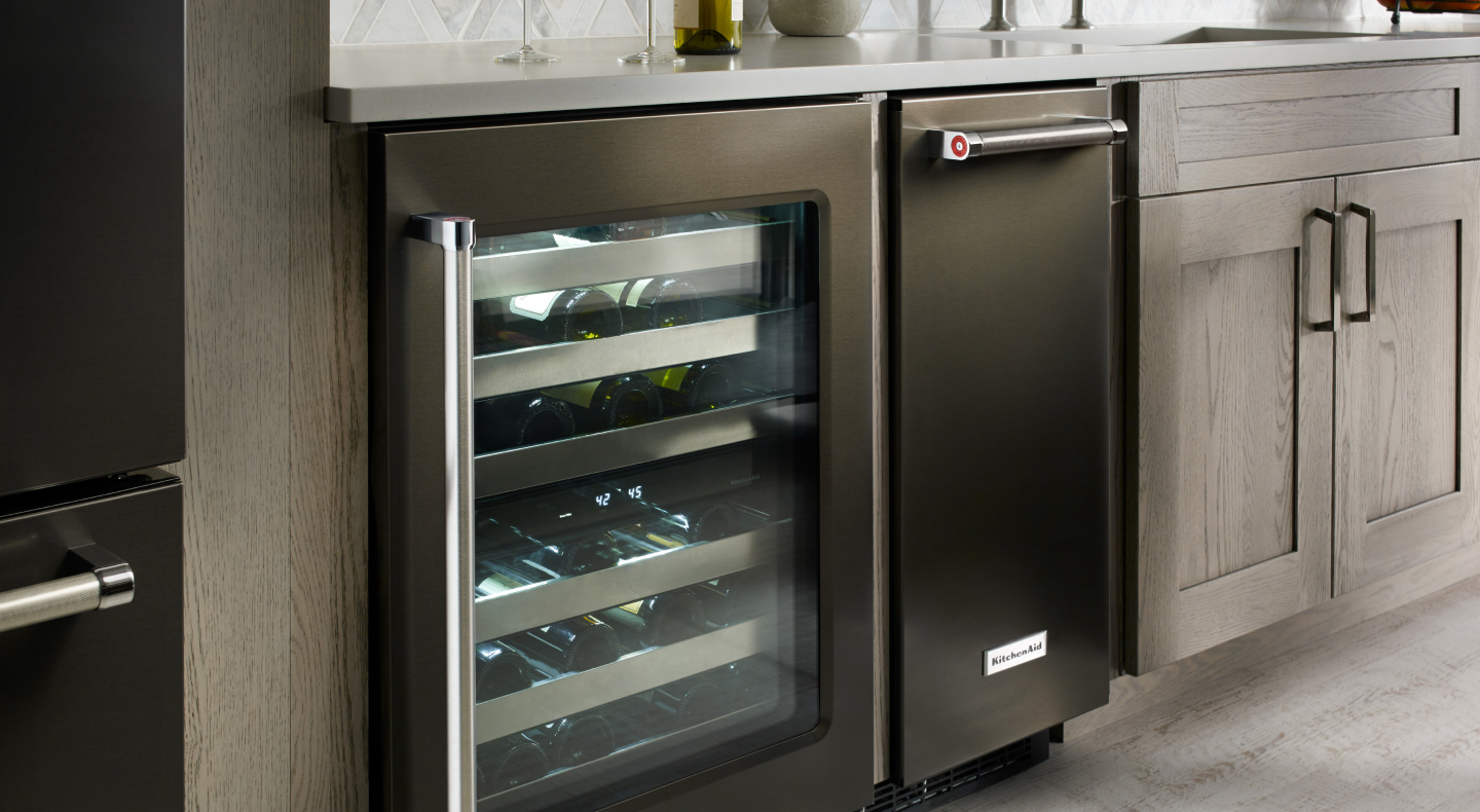 A black KitchenAid® ice maker next to an open wine cooler
