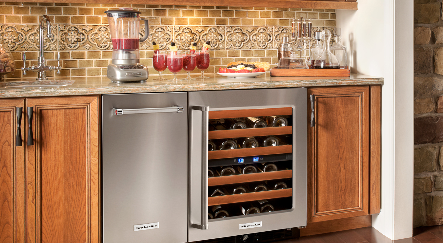 A black KitchenAid® ice maker next to an open wine cooler in a modern kitchen