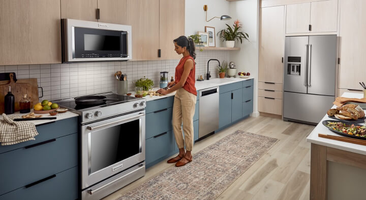 A woman prepping food to the right of her stainless steel range