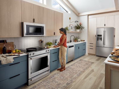 A woman prepping food to the right of her stainless steel range