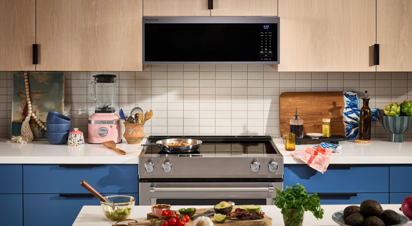 Electric range below a low profile microwave in a kitchen with tan cabinetry
