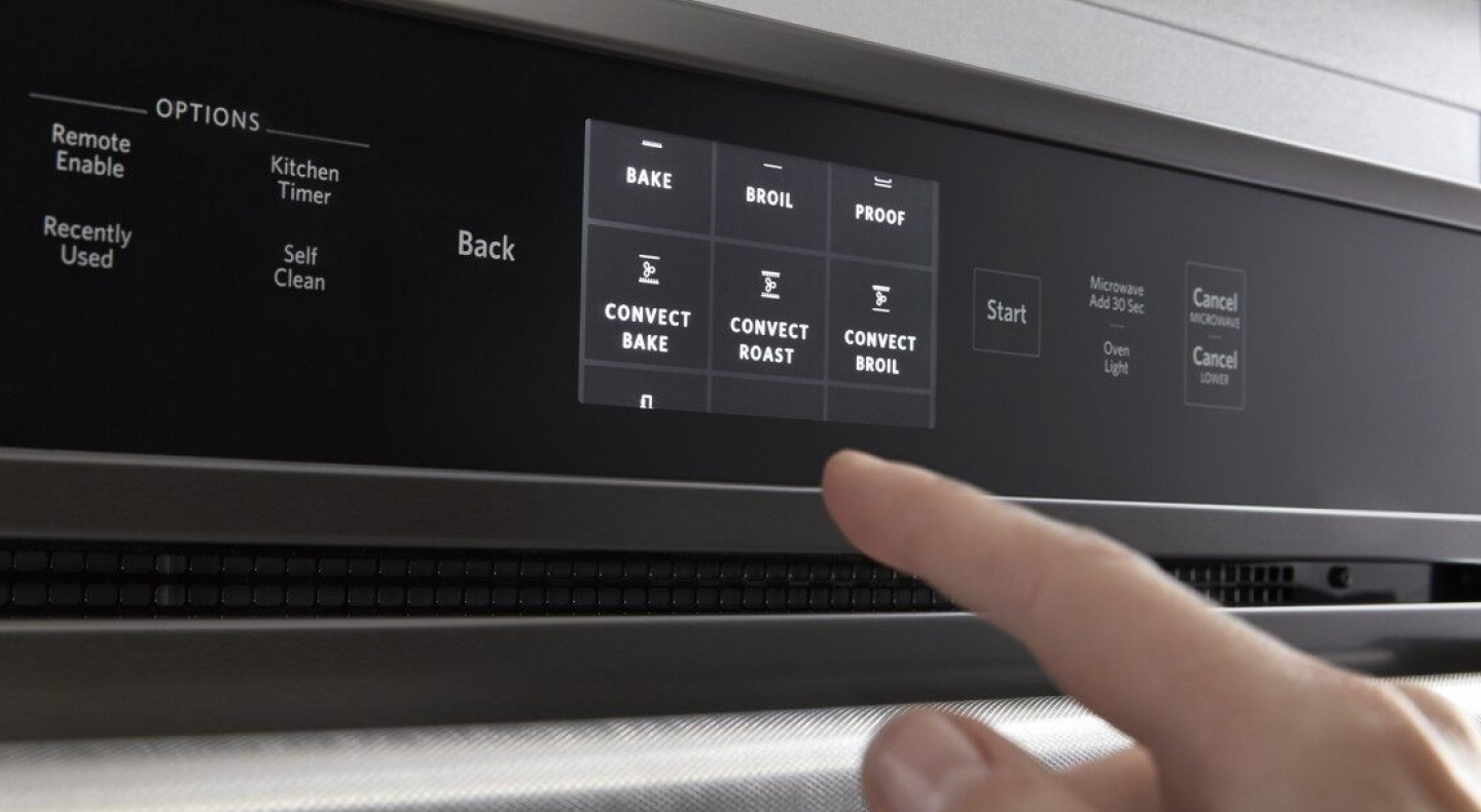 A finger choosing between different settings on a KitchenAid® oven