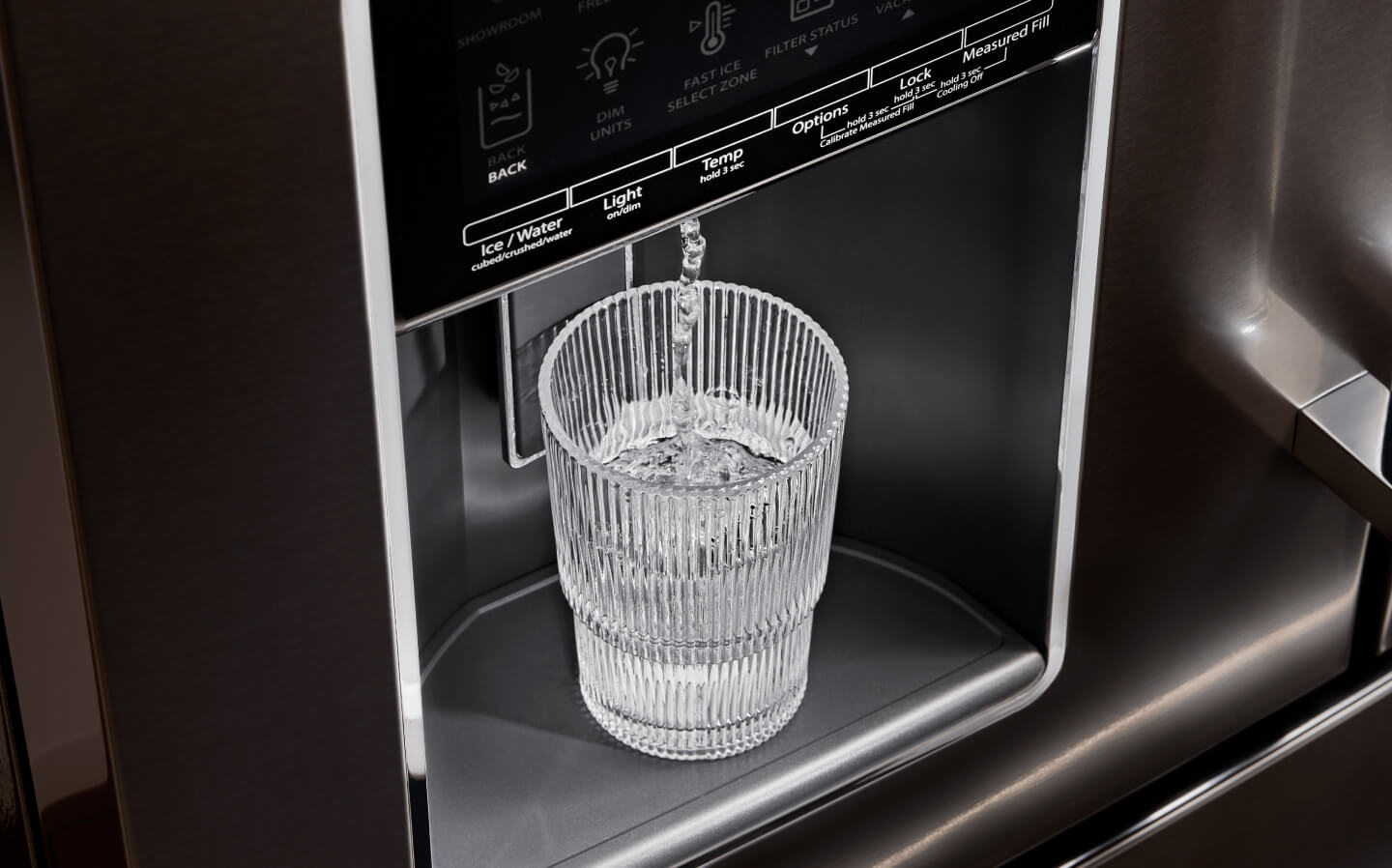 A glass of water filling up at a refrigerator’s exterior ice and water dispenser