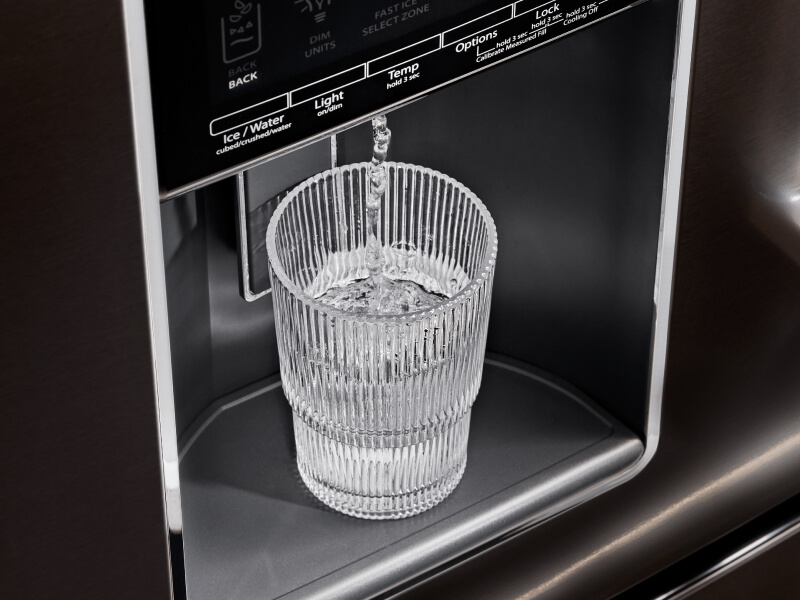 A glass of water filling up at a refrigerator’s exterior ice and water dispenser
