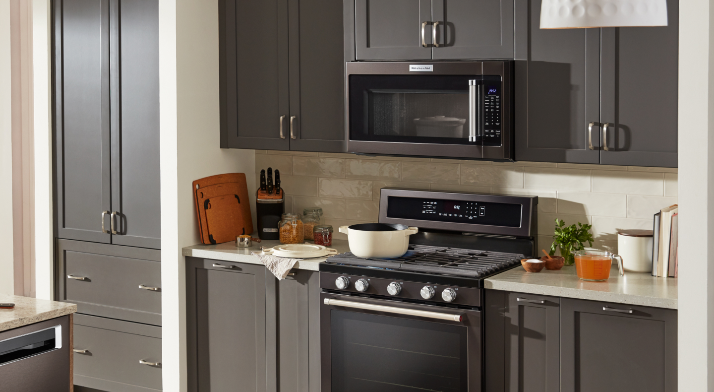 KitchenAid® over-the-range microwave and gas range in brown-gray cabinetry