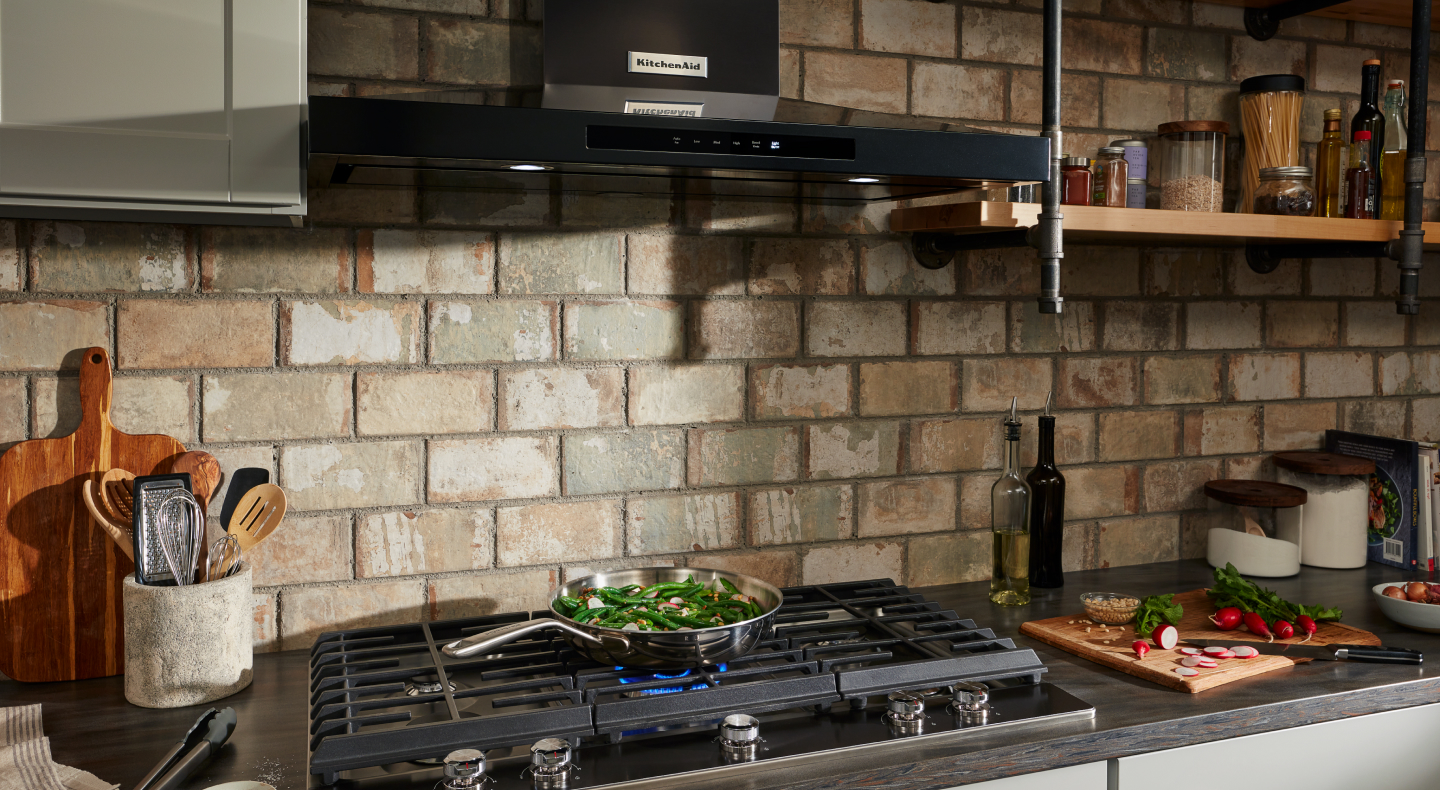 Black KitchenAid® canopy range hood over gas stovetop