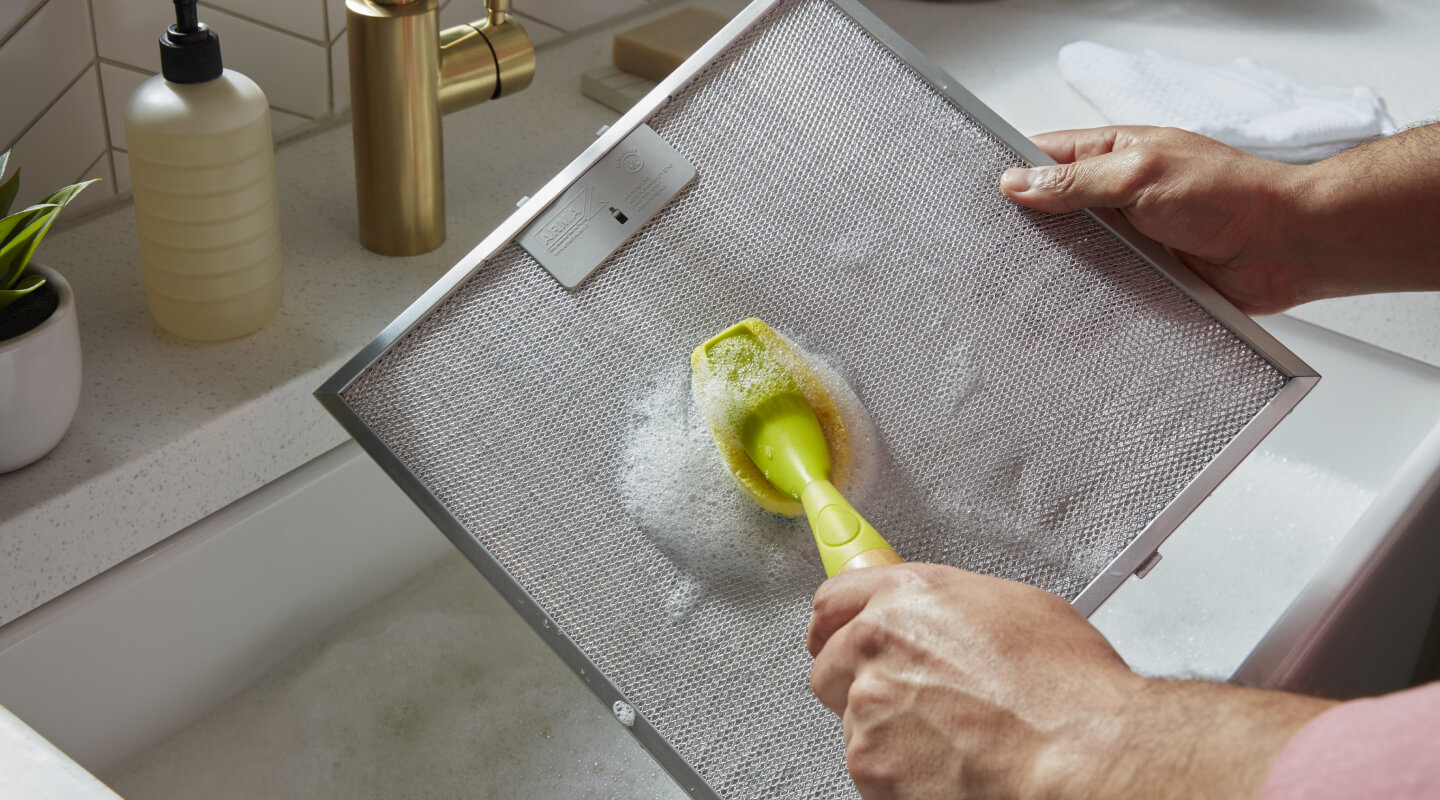 A person cleaning a grease screen