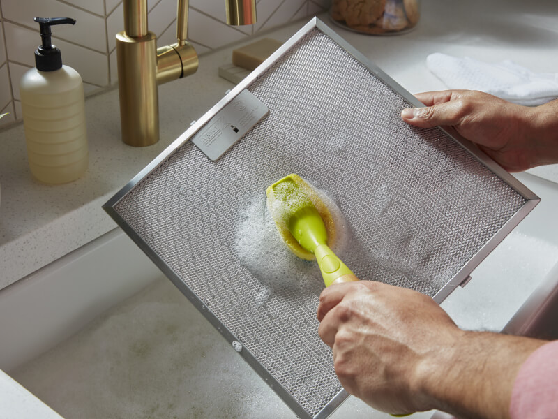 A person cleaning a grease screen